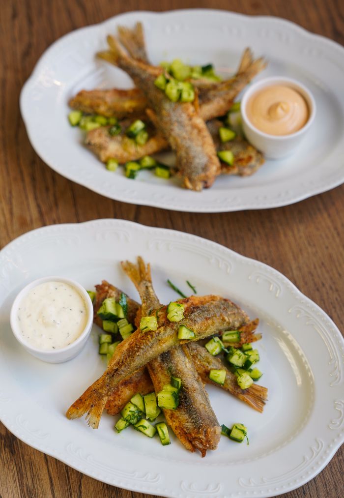 services-01 Two plates of crispy fried fish with vegetables and dipping sauces, perfect for seafood lovers.