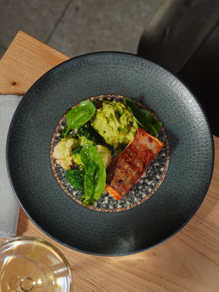 our-story Exquisite salmon served with guacamole and greens on a designer plate, showcasing food artistry.