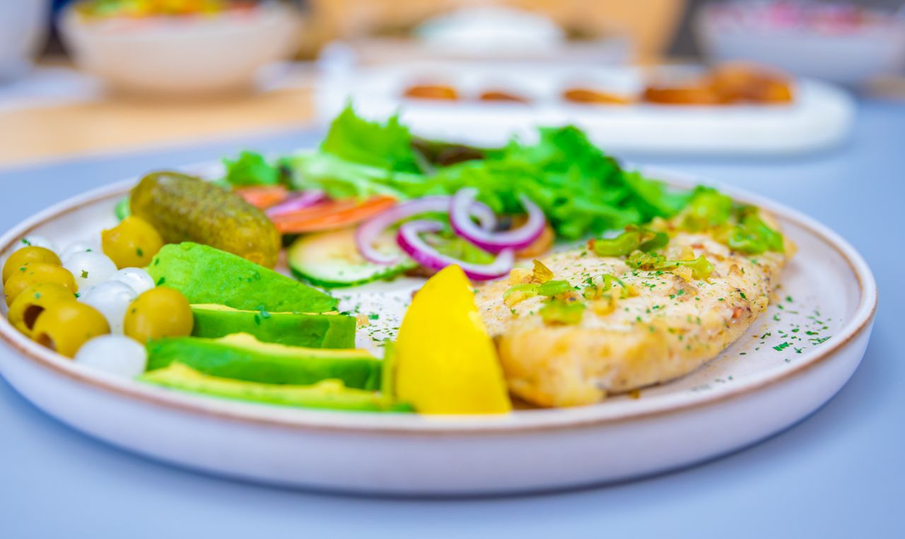 Vibrant dish featuring fresh salad, fish fillet, and assorted vegetables served indoors.